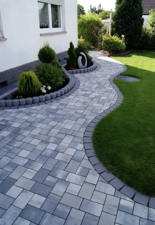 Geschwungener Gartenweg aus Pflastersteinen mit Rasenkante